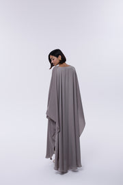 Woman wearing a long, light gray dress against a white background